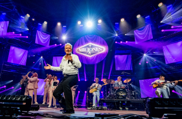 De leden van de tributeband Mr. Jones en Just in case staan op een paars verlicht podium. 