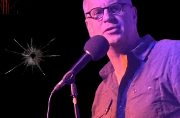 Man met bril zingt in microfoon op filmframe