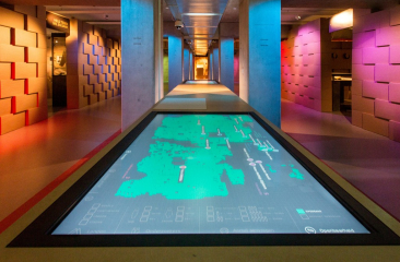 Interactieve tentoonstelling in het Nationaal Archief in Den Haag met digitale kaarten en kleurrijke verlichting
