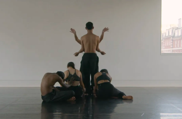 A group of dancers in a studio, with one dancer in the center.