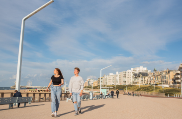 Zwei junge Leute spazieren an der Promenade von Scheveningen.