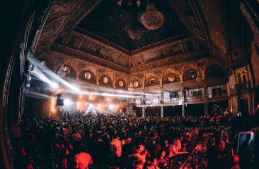 Mensen dansen en vieren in een feestzaal met lichtshows.