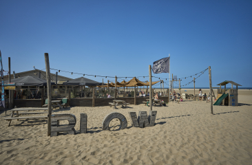 A beach bar named Blow with umbrellas and people on the beach.