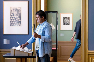 Man met blindegeleidestok voelt aan een werk van Escher tijdens een tour voor blinden en slechtzienden