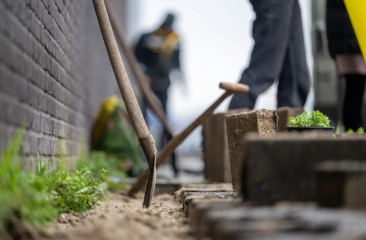 Aanleg van een tuin. Een tuinwerkzaamheden met een schop en mensen op de achtergrond.