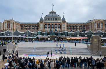 Mensen verzamelen zich voor een evenement bij de Pier, met de achterliggende gebouwen.