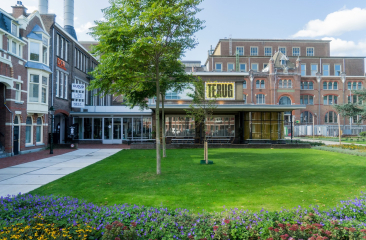  modernes Gebäude mit einem großen gelben Schild und einem grünen Park.