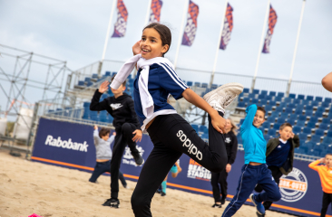 Junges Mädchen tanzt fröhlich am Strand mit anderen Kindern