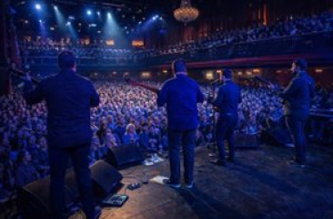 Een band speelt voor een enthousiast publiek in een theater.