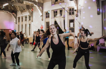 A group of women dancing together in a studio with a cheerful atmosphere.