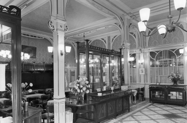 Een elegant interieur van een café met plafondlampen, meubels en bloemen.