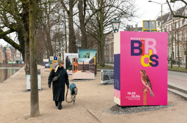 Vrouw loopt met een hond langs tentoonstellingspanelen.