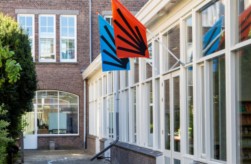 Two colorful flags hang from a building.