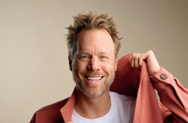 Man met een blij gezicht draagt een roze jas