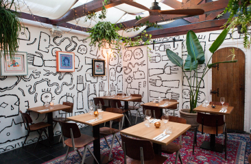 Gemütliches Restaurant mit künstlerischer Wandmalerei von Jamal Armand und Pflanzen.