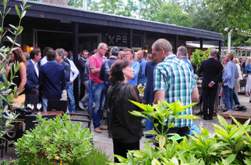 Mensen staan te kletsen op het groene terras van restaurant Pex