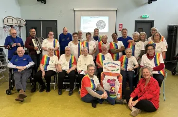 Koor van dames op leeftijd met grijs haar gekleed in witte t-shirts met regenboogkleuren