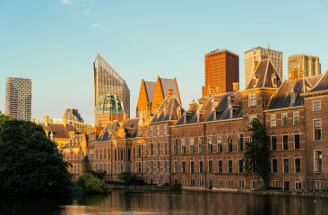 Het Binnenhof en de Hofvijver gefotografeerd in de avondzon met op de achtergrond de moderne skyline van Den Haag