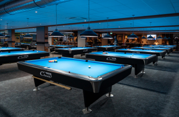 A spacious billiard room featuring several blue billiard tables.