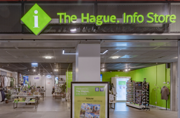 Grüne Fassade des The Hague Info Store mit Auslagen.