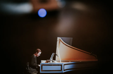A pianist playing a grand piano in the dark.