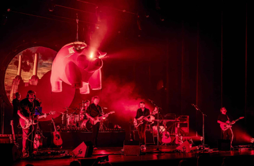 Band speelt live op een podium met een grote luchtballon.