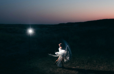 A woman dances with a translucent fabric in twilight.