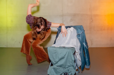 A dancer in a creative pose with clothing items.
