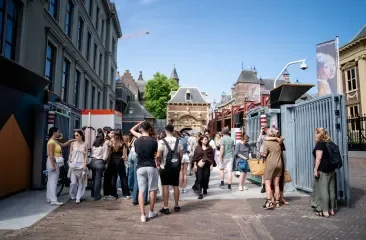 Mensen staan in een drukke straat met historische gebouwen.