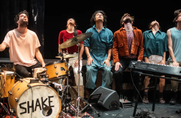 Six performers in a musical act on stage