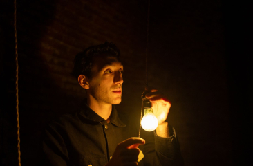 Man in het donker houdt een brandende gloeilamp vast