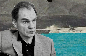 Man in grijs pak met zee en rotsen op achtergrond