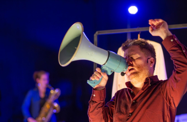 Man zingt met megafoon tijdens muzikale voorstelling