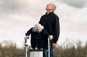 Man die omhoog kijkt en een op leeftijd dame die staat met een rollator