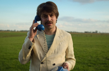 Joost Oomen met blauwe telefoon in weiland