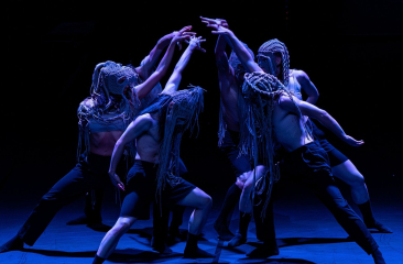 Dansers met maskers in expressieve choreografie
