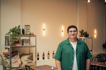 Hizir Cengiz in een sfeervol café met flessen en planten