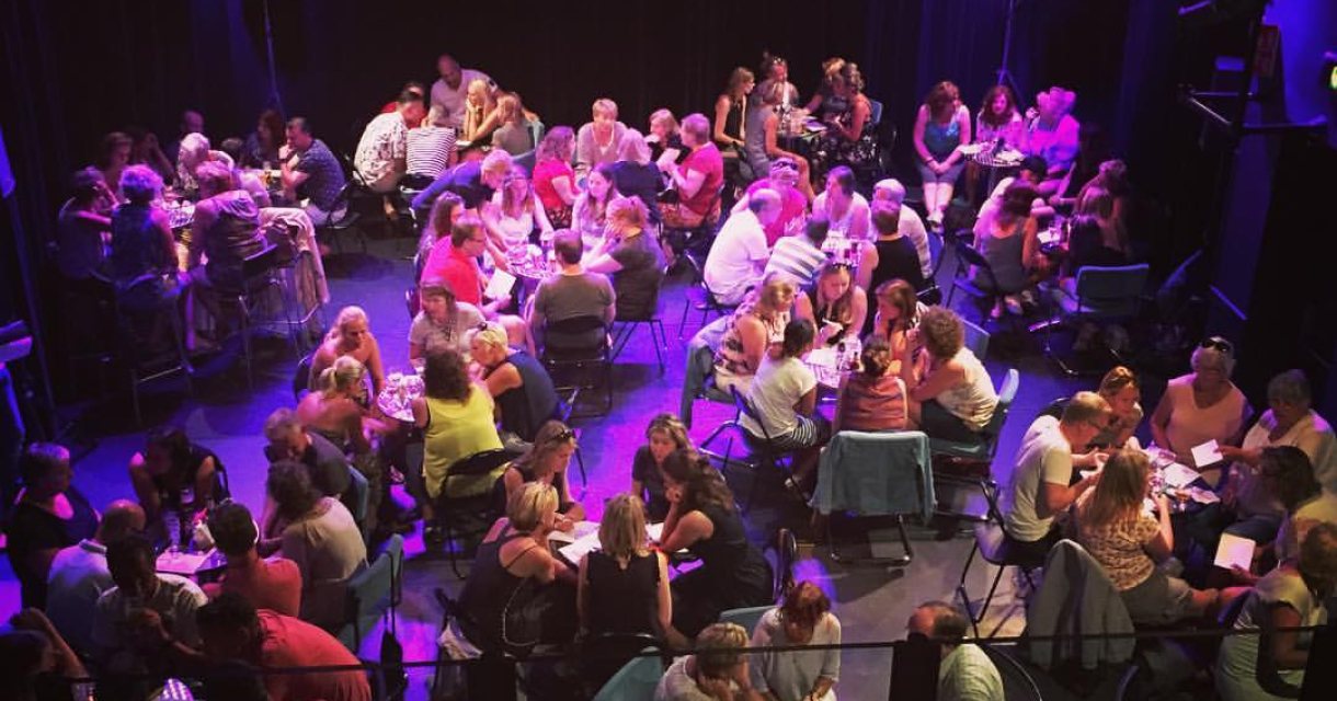 De theaterzaal vol met mensen aan tafels voor de Pubquiz