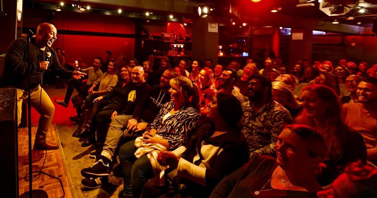 Comedian speelt voor lachend publiek in clubzaal Comedian speelt voor lachend publiek in clubzaal