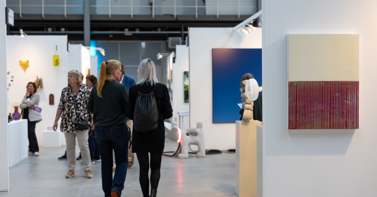 Bezoekers in een hal met kunstwerken tijdens Art The Hague