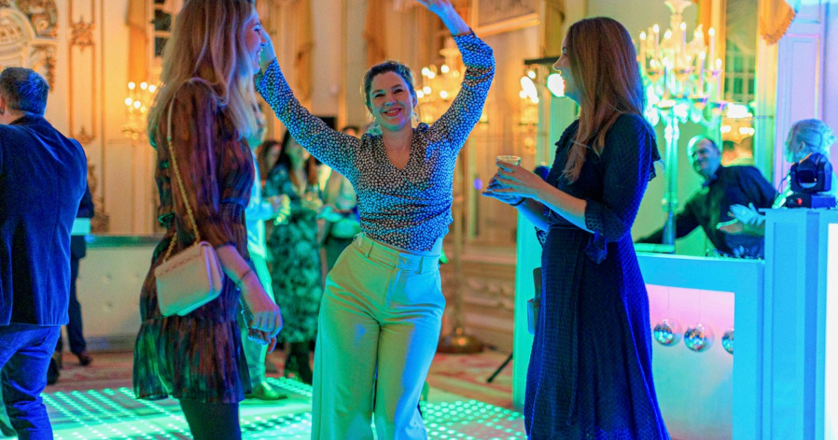 Drie dames die staan te dansen op een verlichte dansvloer Drie dames die staan te dansen op een verlichte dansvloer