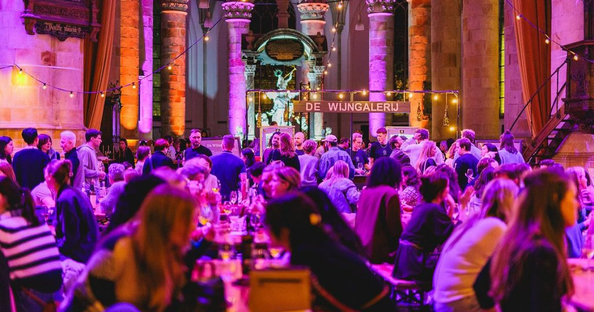 Bezoekers van Het Wijn Festijn in de Grote Kerk aan tafels Bezoekers van Het Wijn Festijn in de Grote Kerk aan tafels