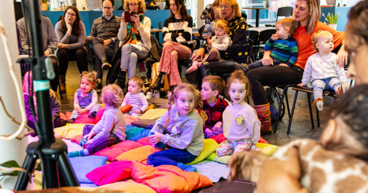 Kinderen en ouders luisteren naar een verhaal uit een boek