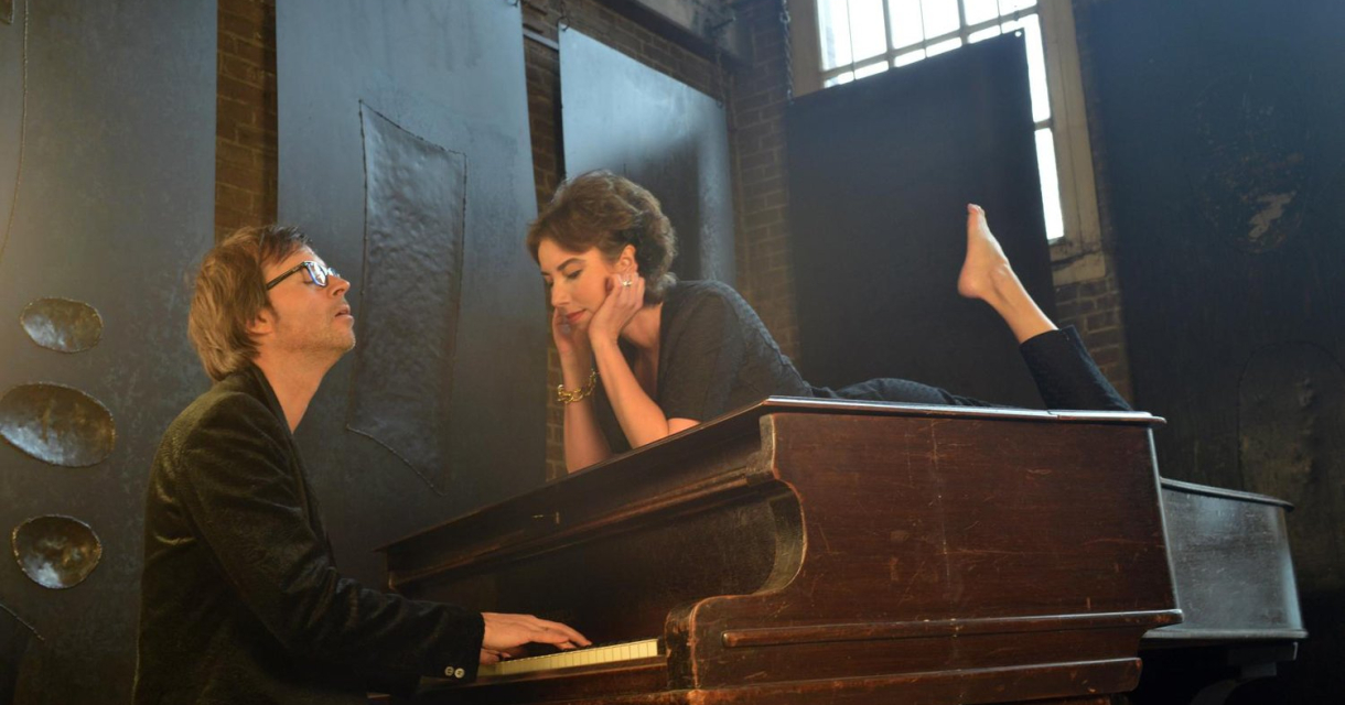 Britta Maria liggend op een piano en Maurits Fondse