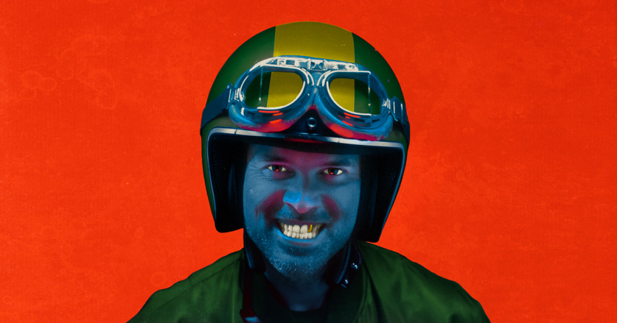 Een persoon gekleed in een groene pilotenjas en een helm met bril. 