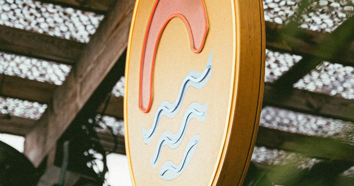 Rond uithangbord met golven bij strandlocatie.