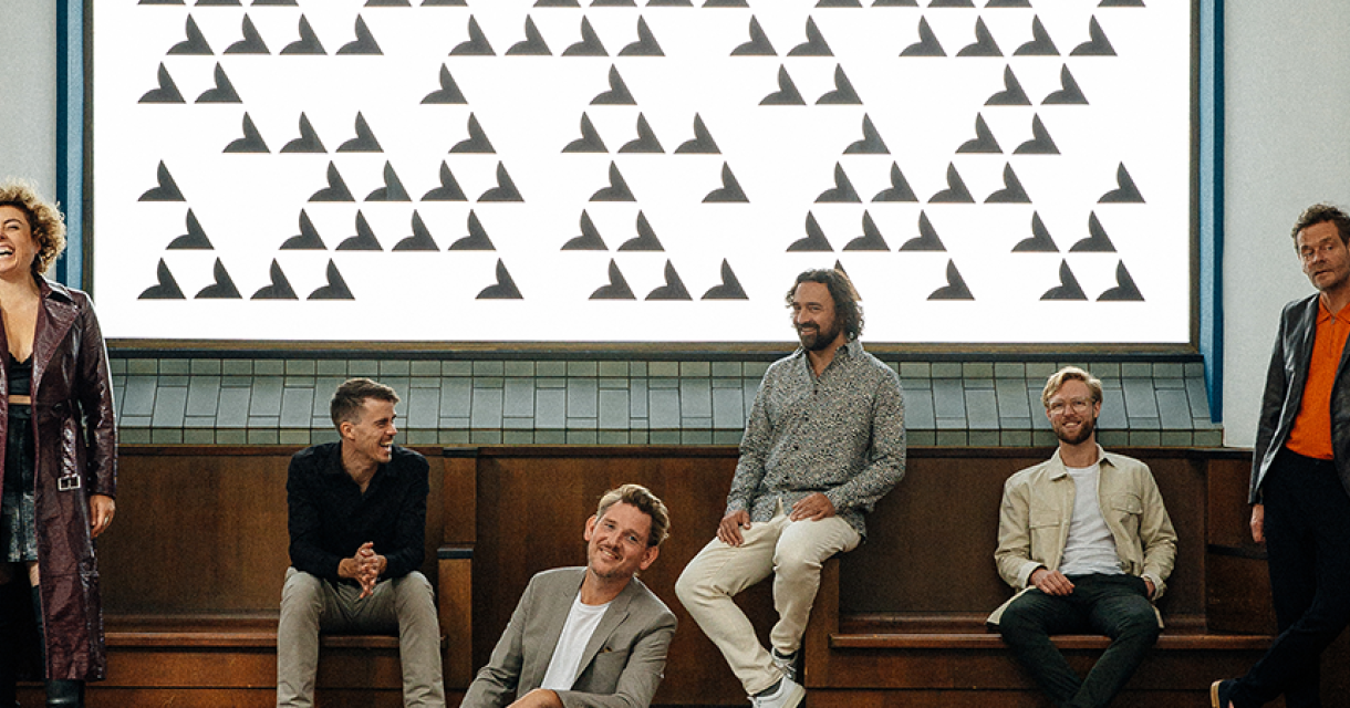 De band Kraak & Smaak lachend voor kunstwerk met driehoeken De band Kraak & Smaak lachend voor kunstwerk met driehoeken