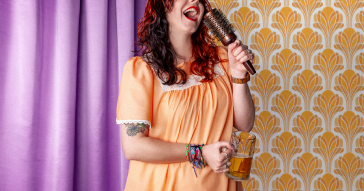 Vrouw in nachtjapon zingt met haarborstel en pul bier in slaapkamer setting, als slapstick vroegzat party