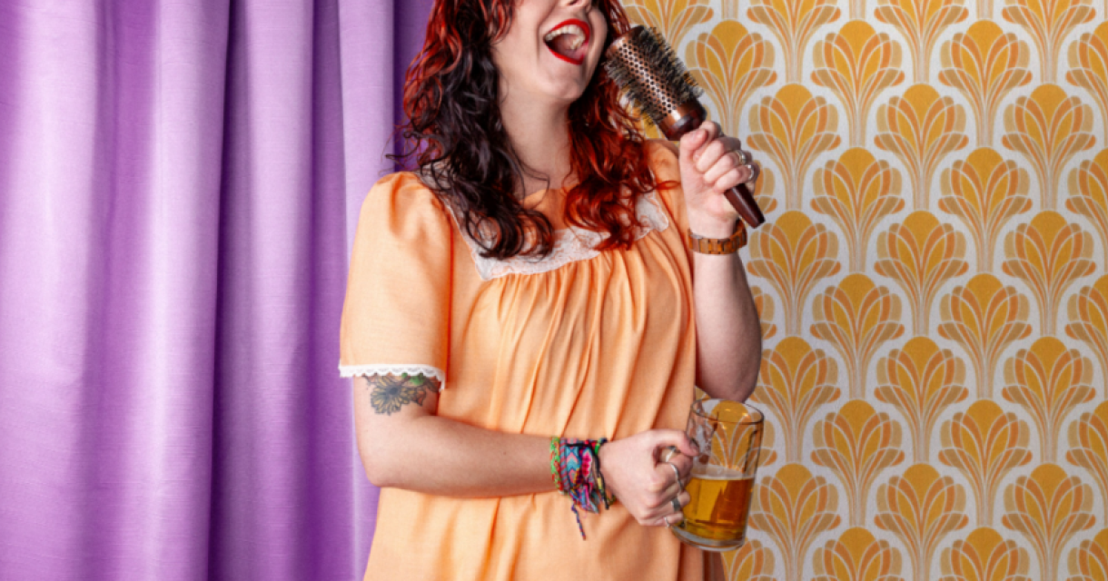 Vrouw in nachtjapon zingt met haarborstel en pul bier in slaapkamer setting, als slapstick vroegzat party