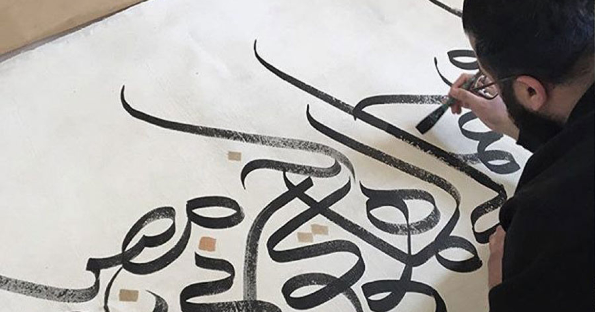 Man schildert Arabische kalligrafie op doek Man schildert Arabische kalligrafie op doek